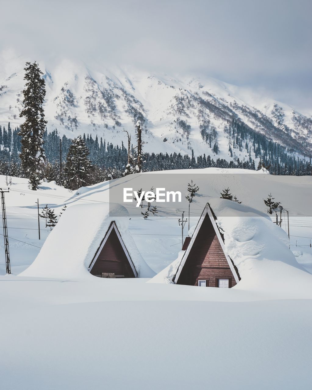 Snow covered houses against mountains and sky