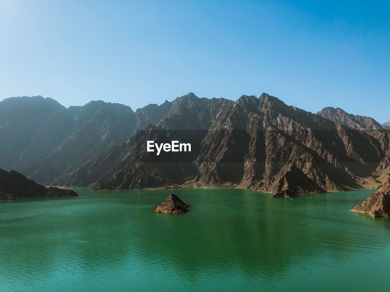 Scenic view of sea and mountains against clear blue sky