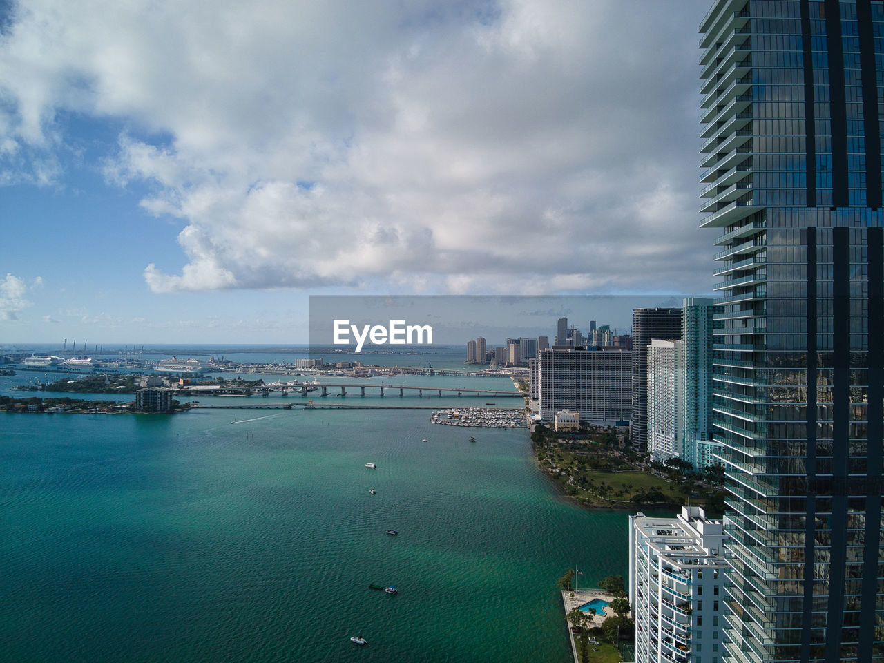 SEA BY MODERN BUILDINGS AGAINST SKY