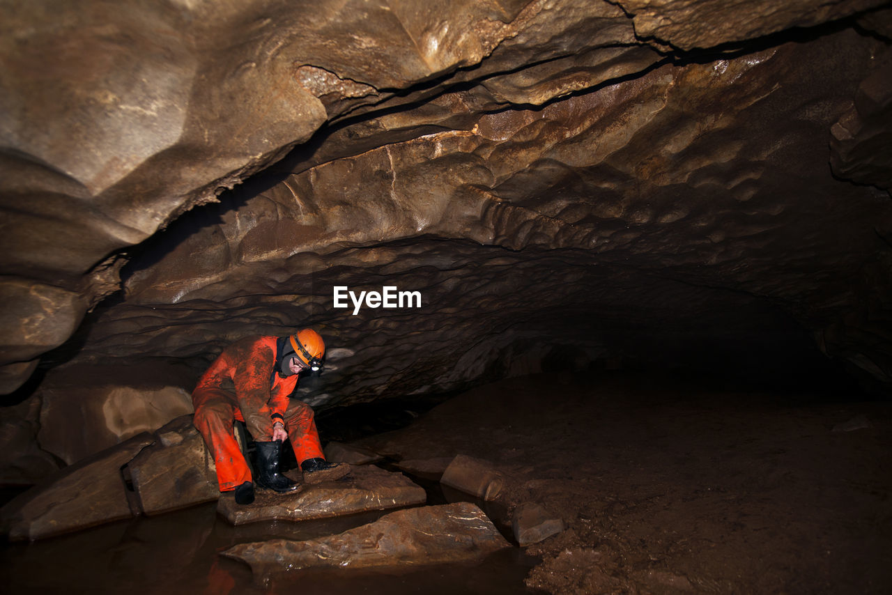 Manual worker cleaning boot while sitting in cave