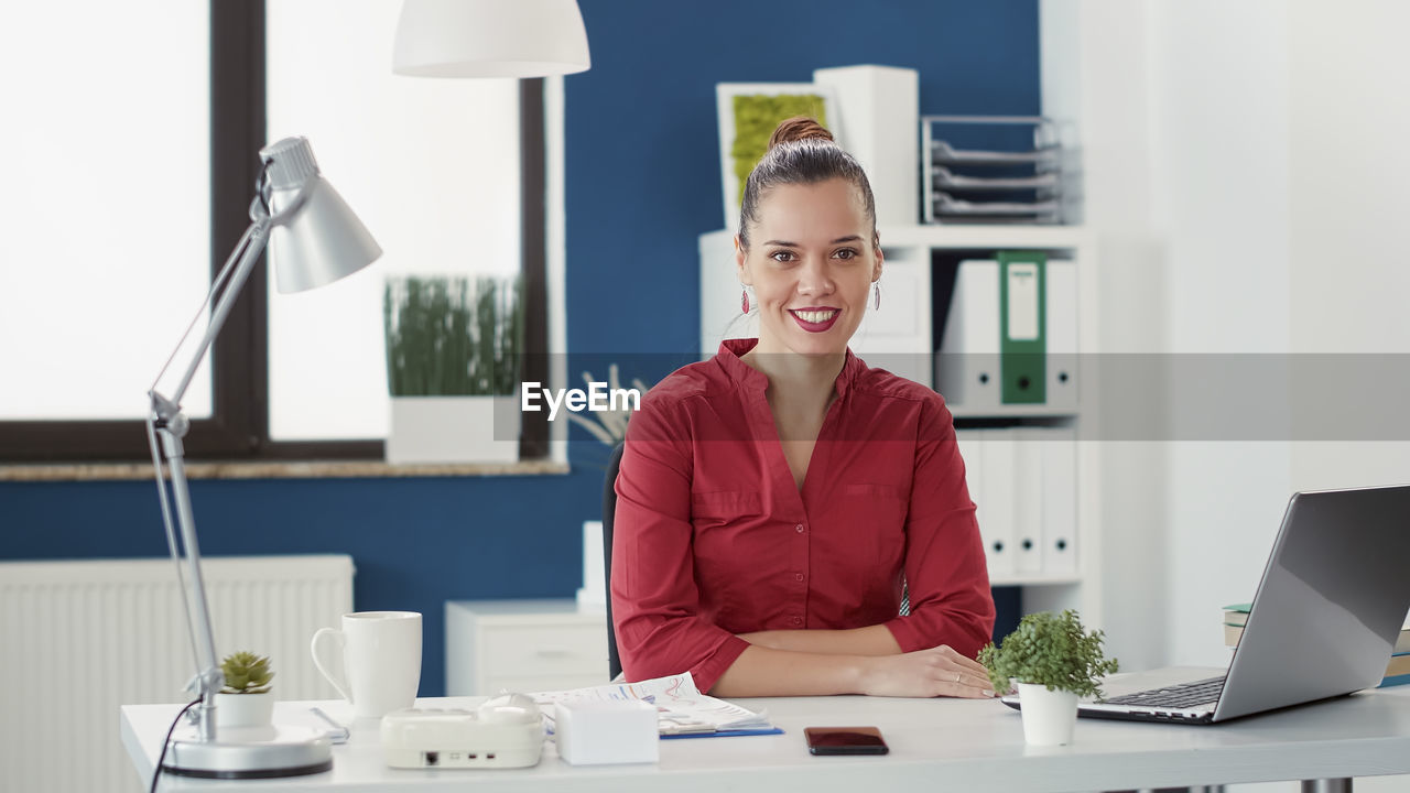 Portrait of businesswoman sitting at desk in office