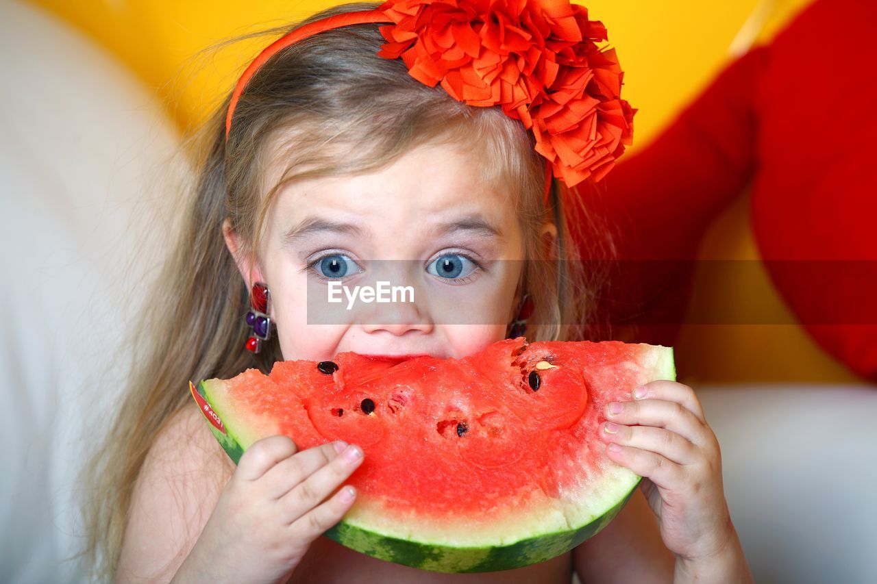 A 3 year old girl eats a watermelon.