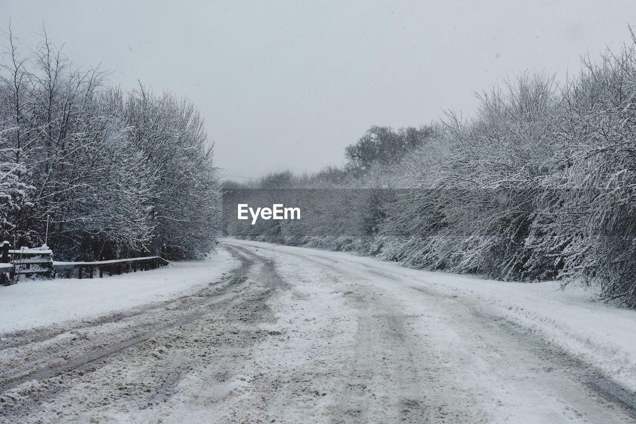 ROAD PASSING THROUGH SNOW COVERED LANDSCAPE