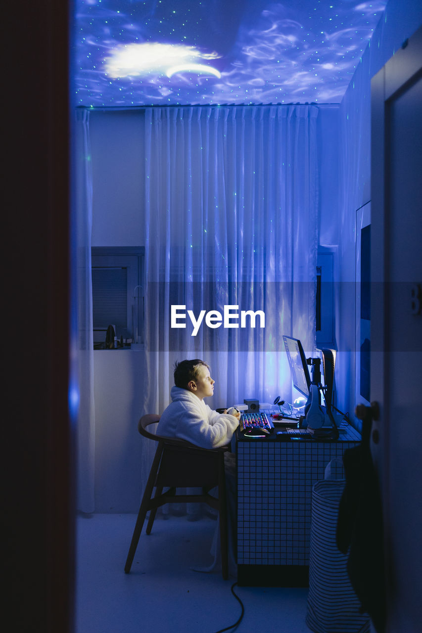 Boy at desk using computer at night