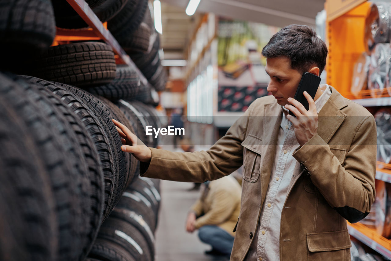Man talking on phone choosing tire at shop