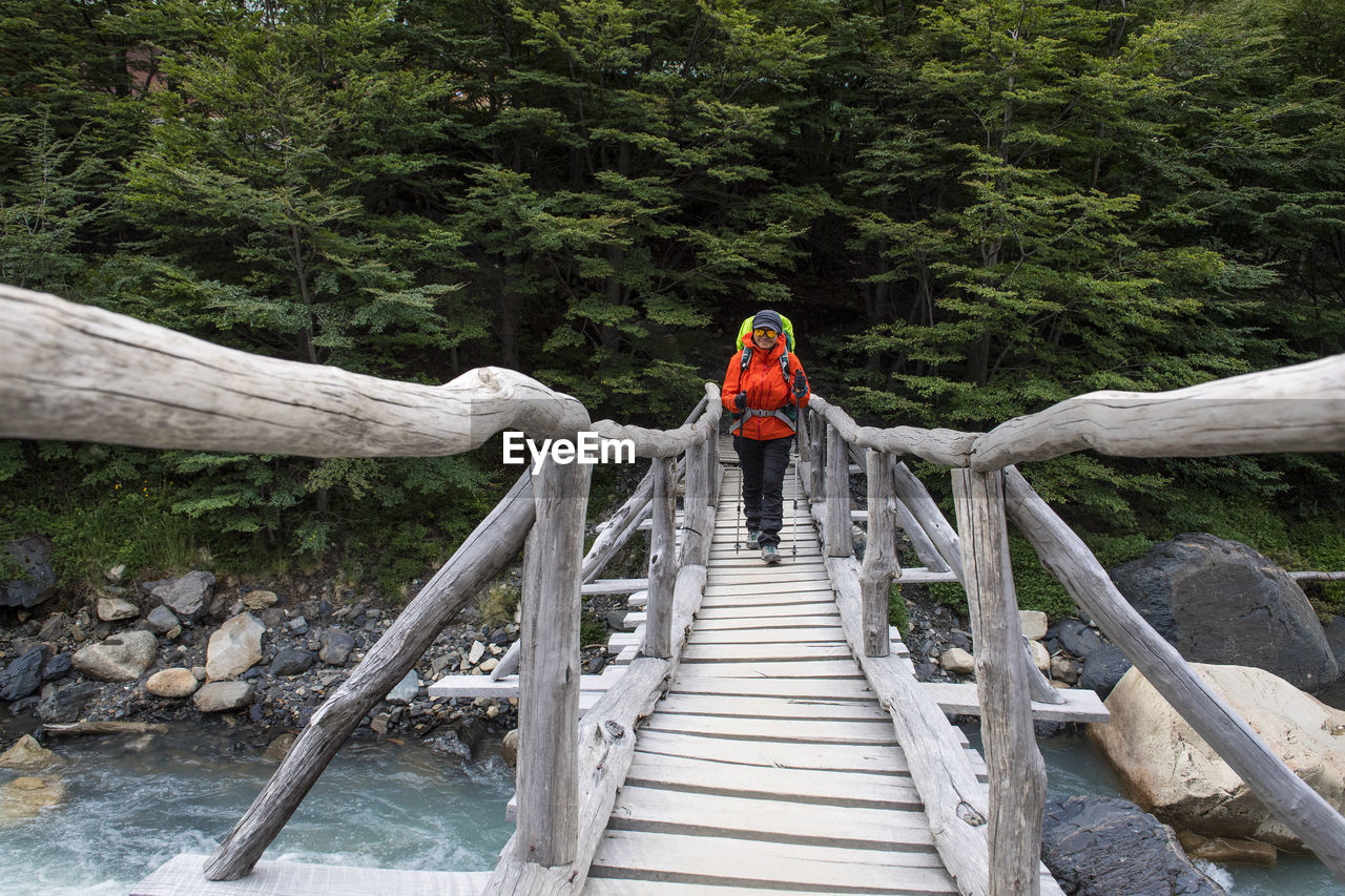 Female hiker crossing wooden bridge on the way up to torres del paine