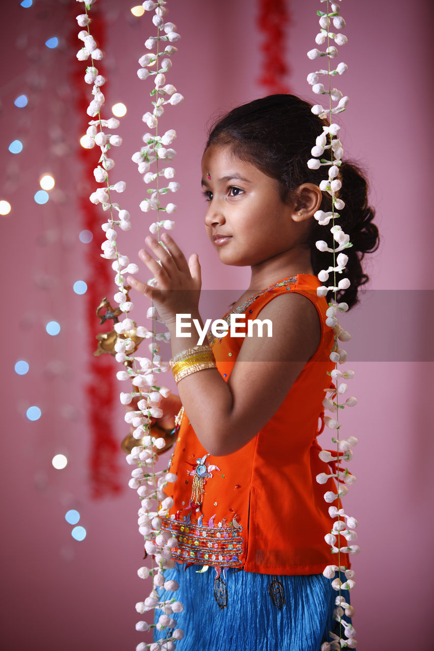 SIDE VIEW OF A GIRL STANDING AGAINST WALL