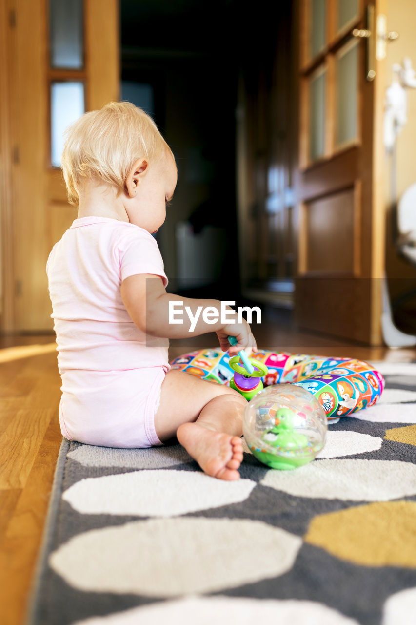 Adorable little girl playing while sitting on floor at home