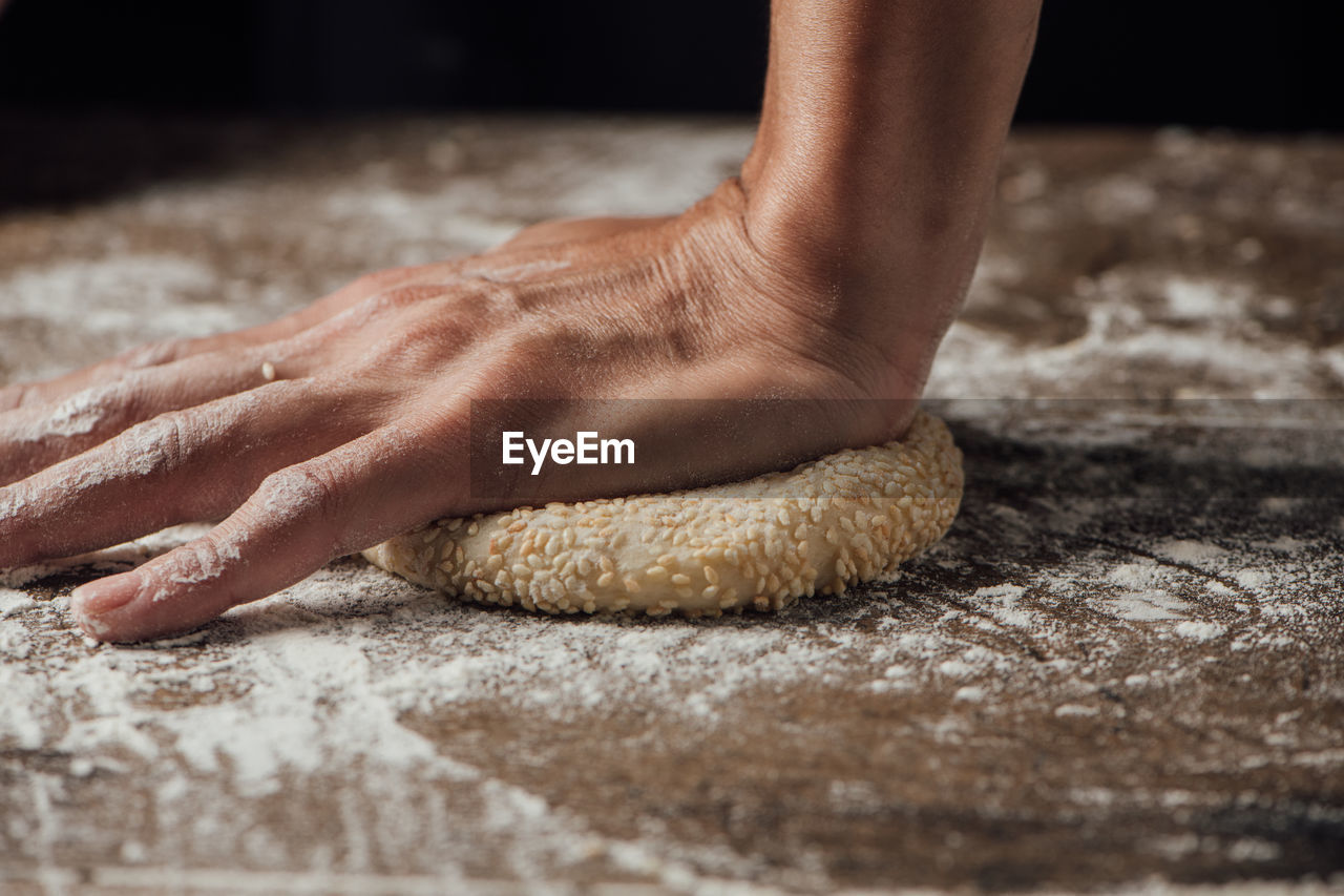 Cropped hand kneading dough on table