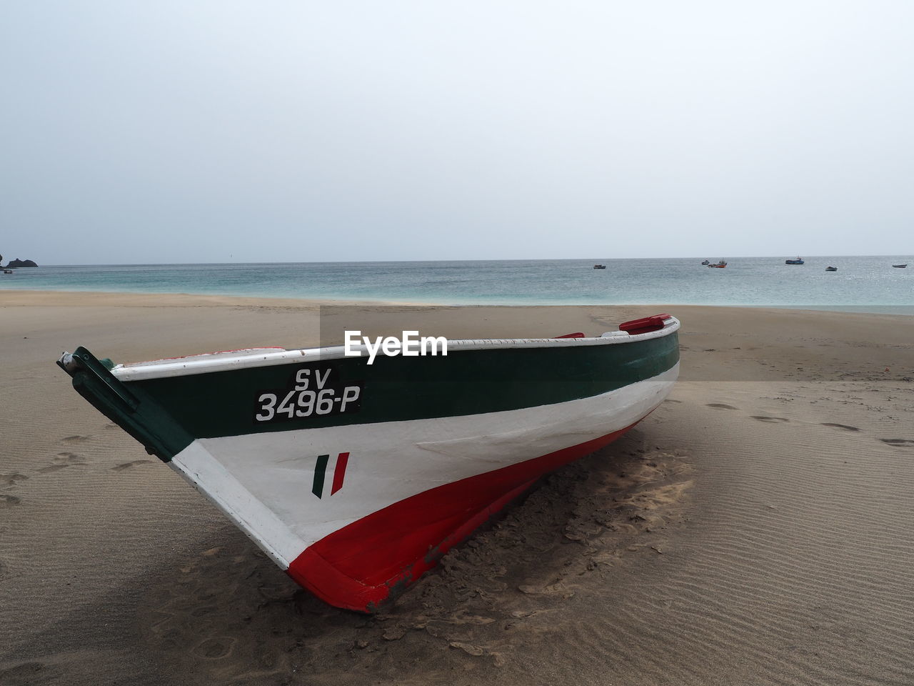 Boat moored on beach against clear sky