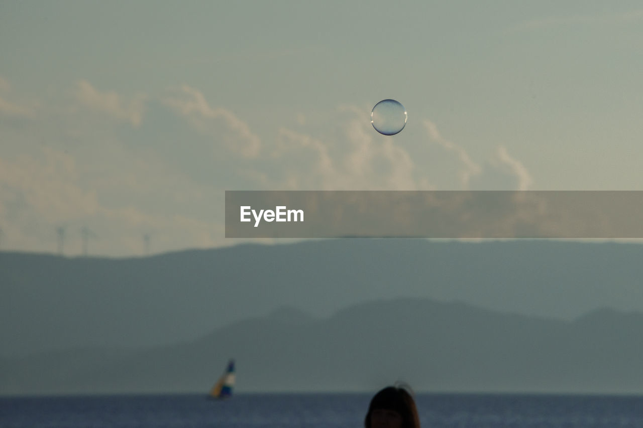 HOT AIR BALLOON OVER SEA AGAINST SKY