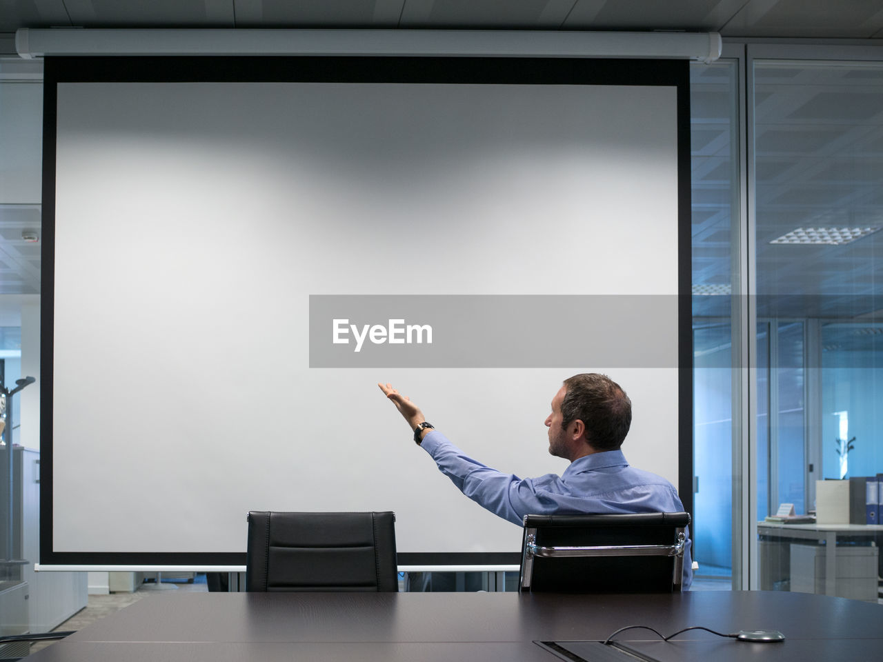 Businessman pointing at projection screen in office