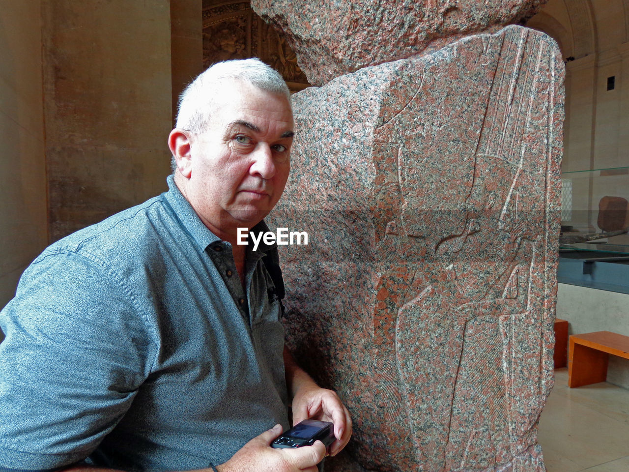 Portrait of senior man holding camera at museum