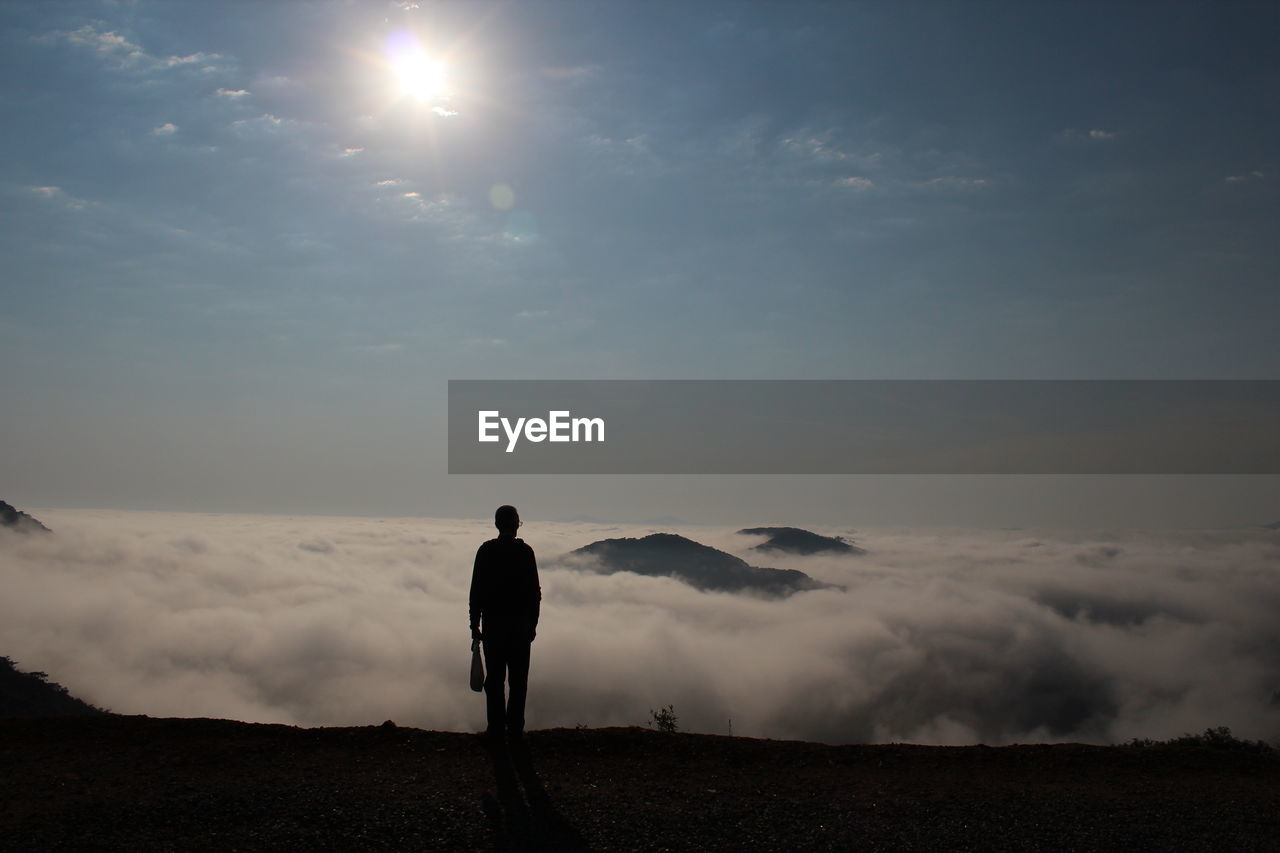 Rear view of man standing against cloudscape