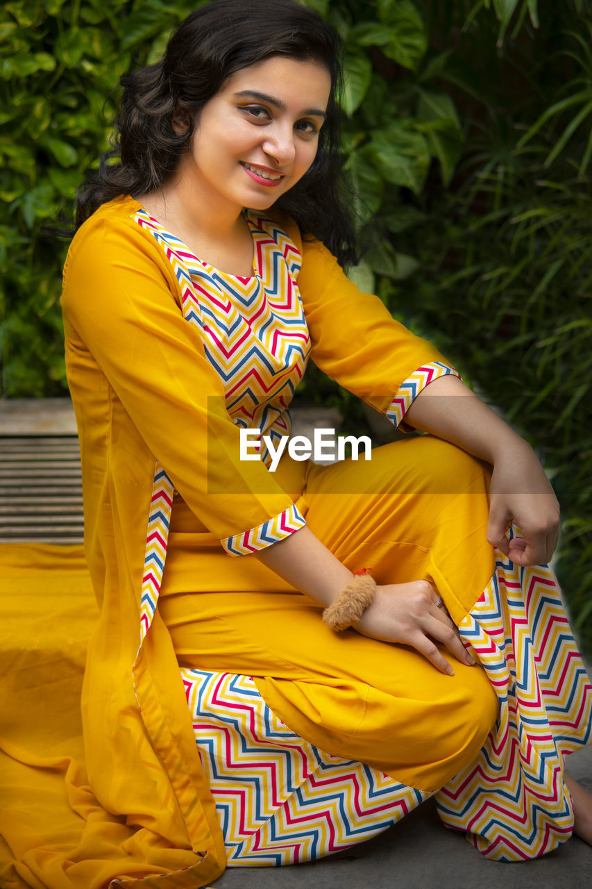 portrait of smiling young woman sitting on field