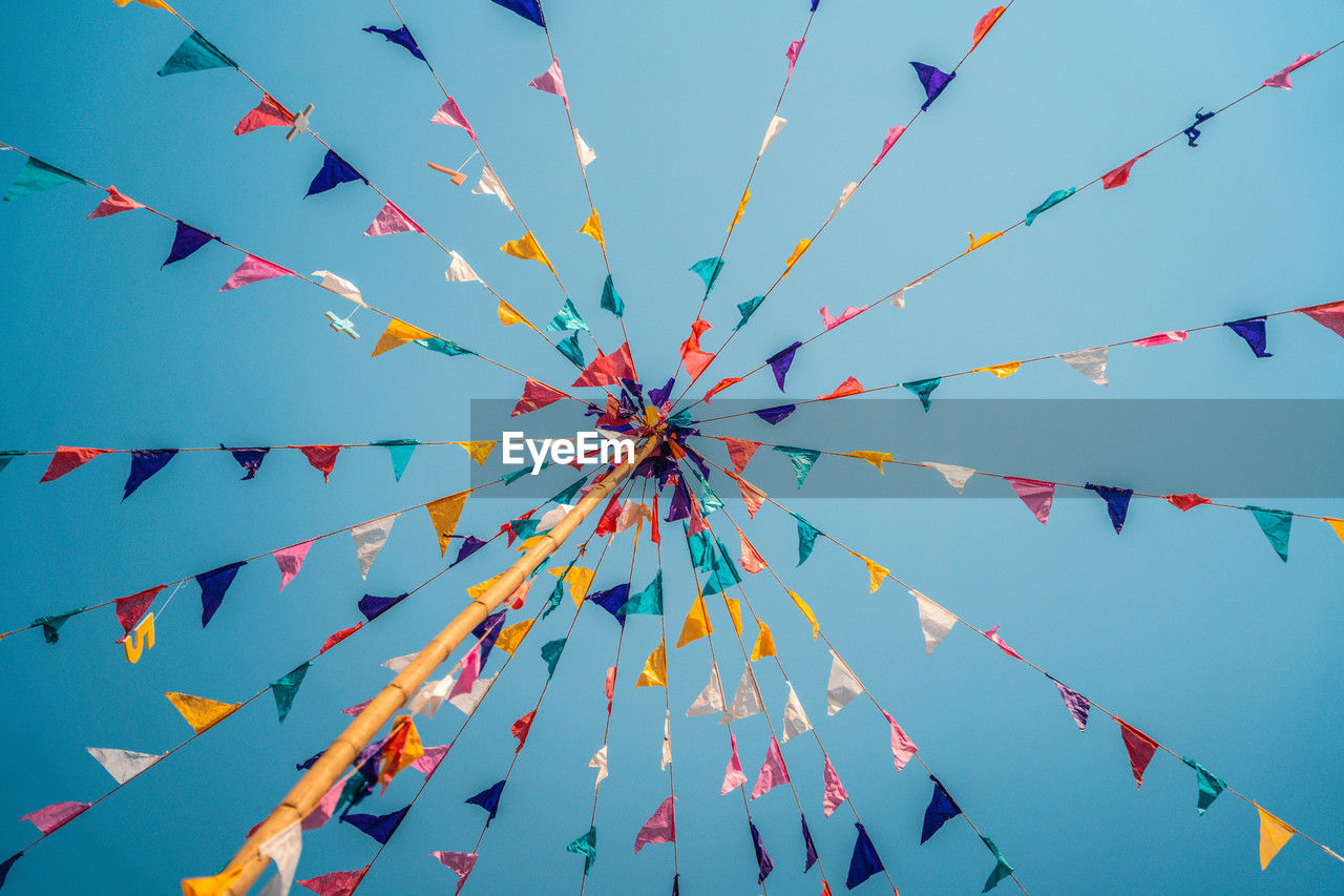 celebration, multi colored, toy, sky, event, decoration, kite sports, no people, bunting, blue, line, tradition, large group of objects, nature, low angle view, streamer, hanging, flower, flying, windsports, outdoors, day, traditional festival, clear sky, wind