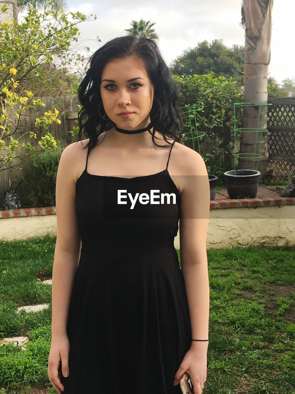 Beautiful young woman in black dress standing at park