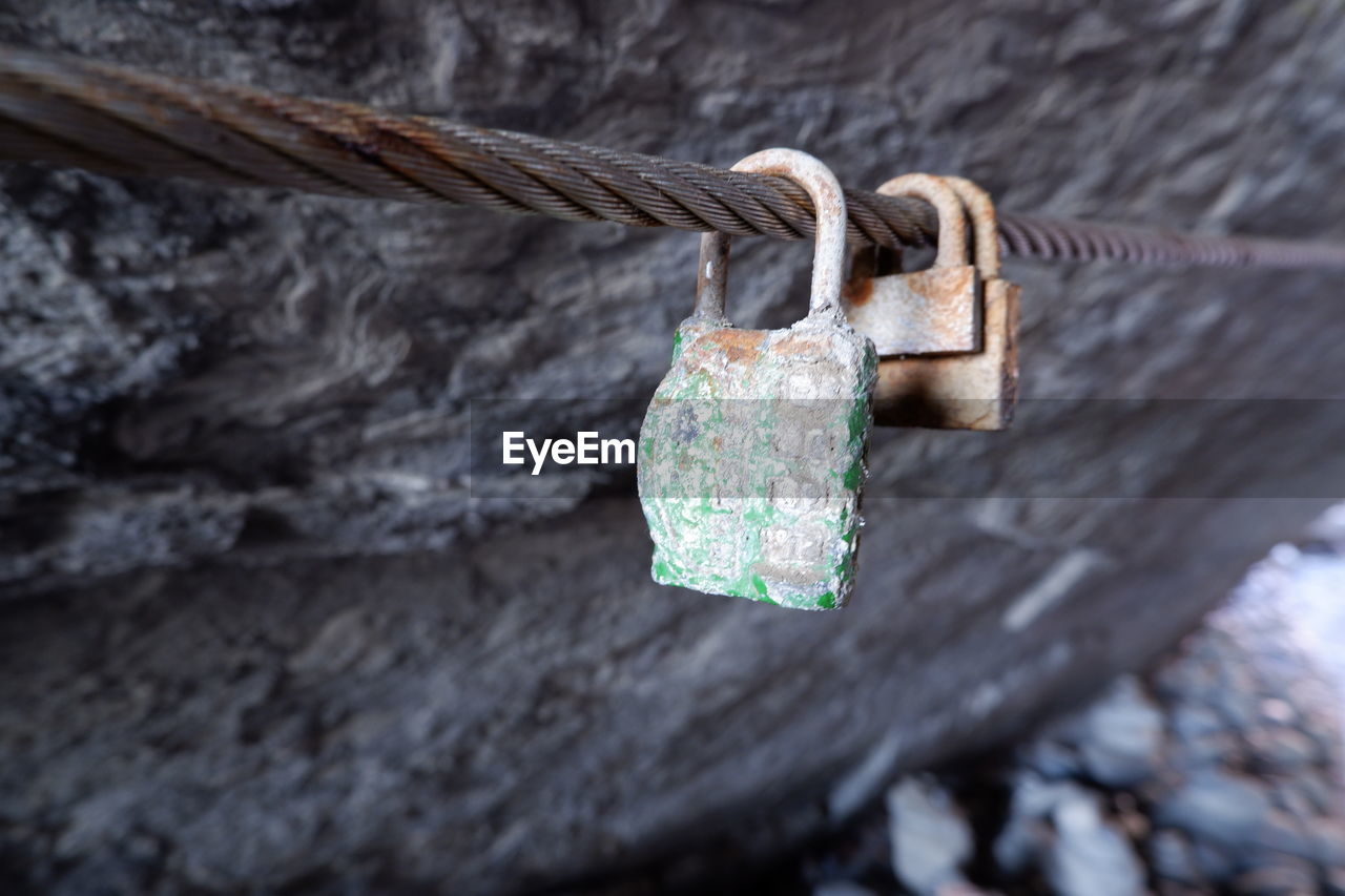 CLOSE-UP OF PADLOCKS HANGING ON METAL