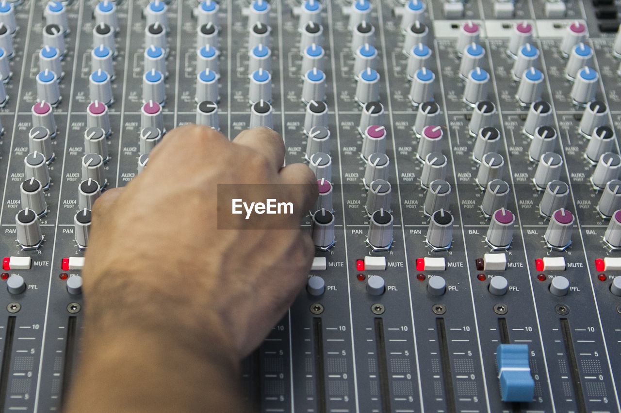 Cropped hand of man mixing music at recording studio