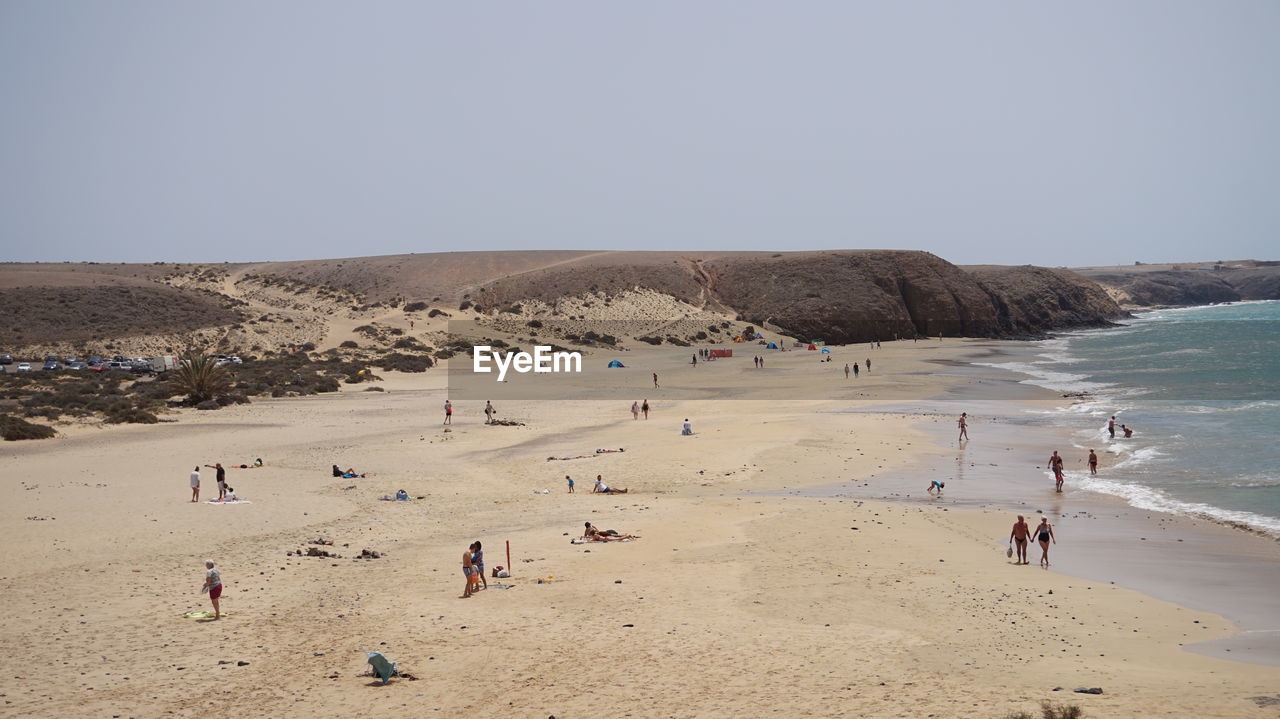 Group of people on beach against clear sky