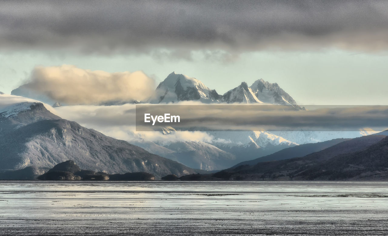 Scenic view of sea and snowcapped mountains against sky