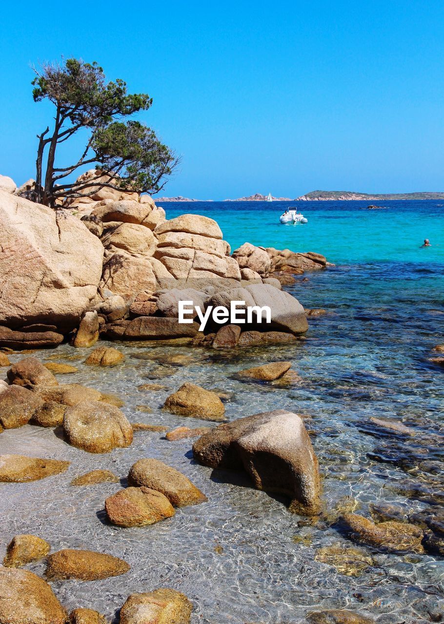 Rocks on beach against clear blue sky