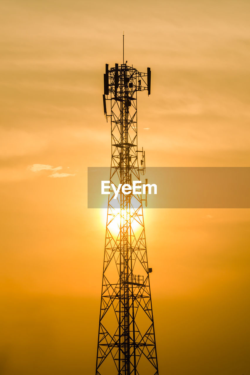 Low angle view of silhouette communications tower against sky during sunset