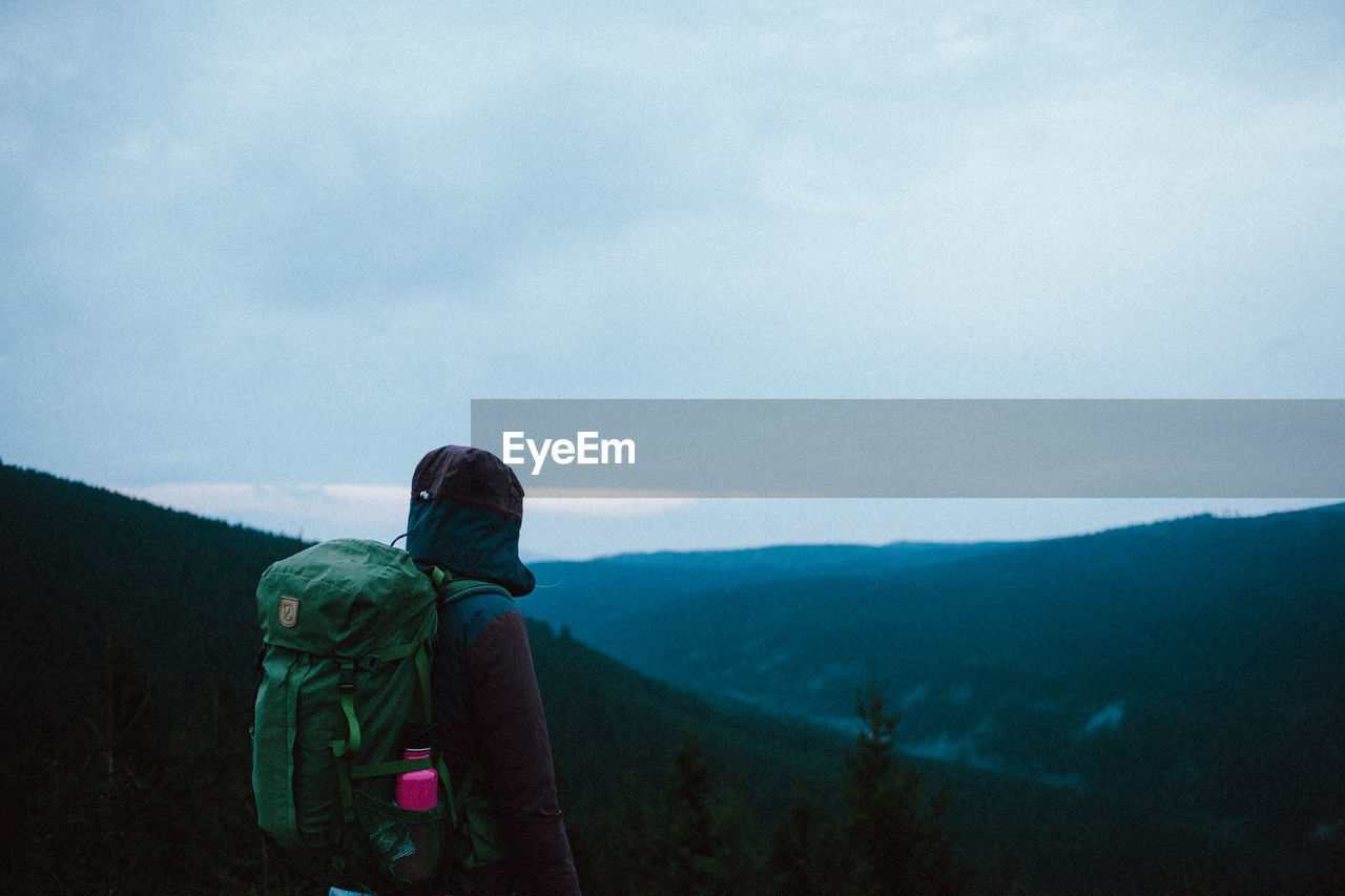 Rear view of backpack man looking at mountain against sky