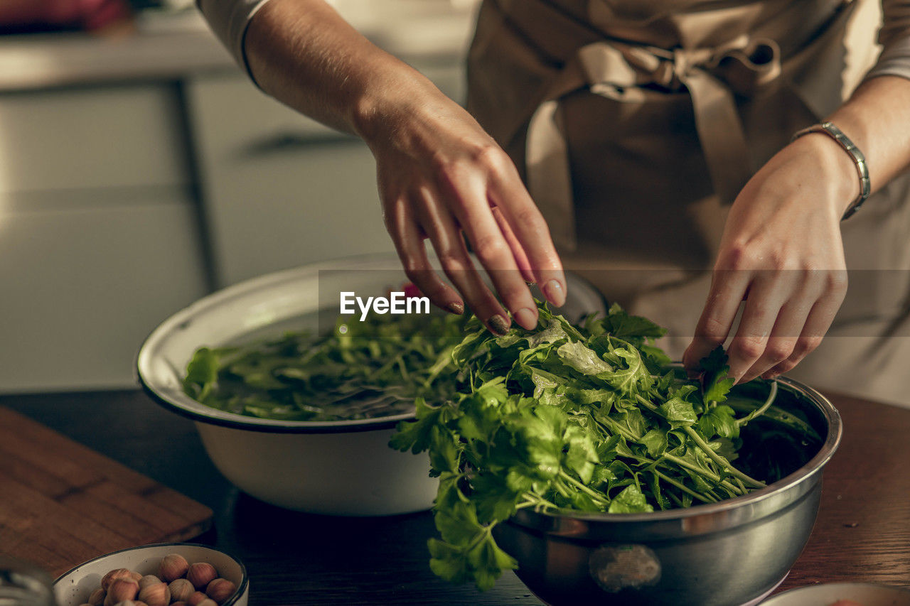 Hands of a young woman in the kitchen is washing parsley greens for a vegan morning