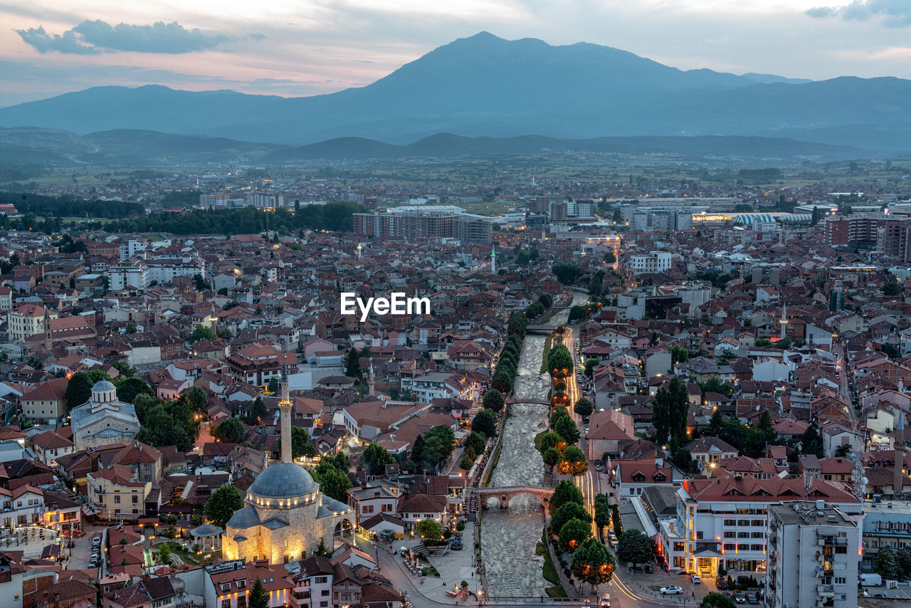 Aerial view of cityscape by mountain at dusk