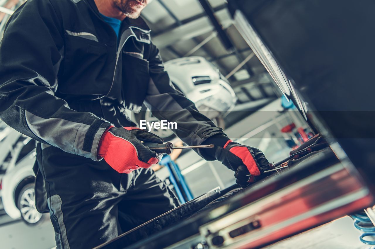 Midsection of man repairing car in garage