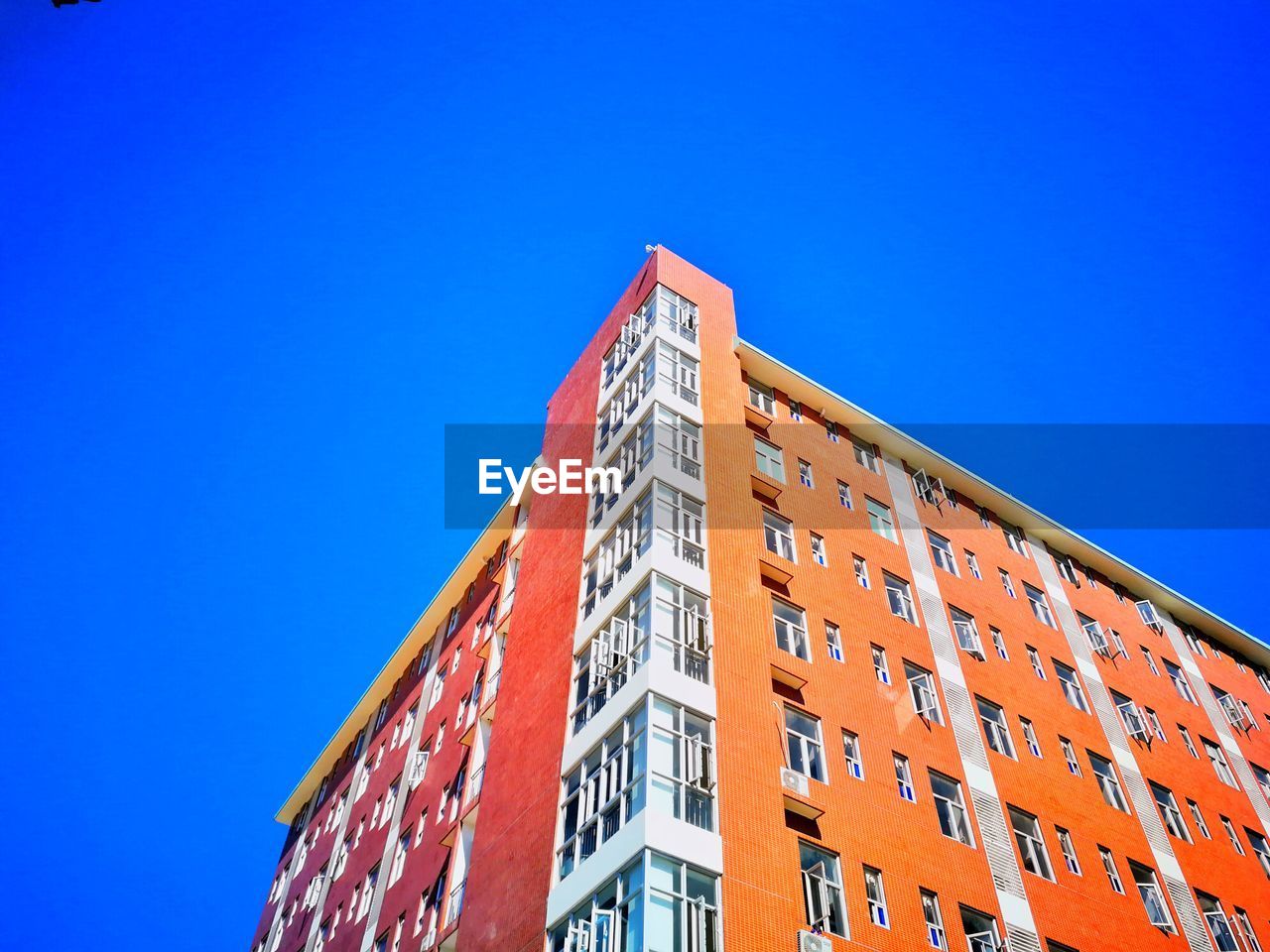 LOW ANGLE VIEW OF RED BUILDING AGAINST BLUE SKY