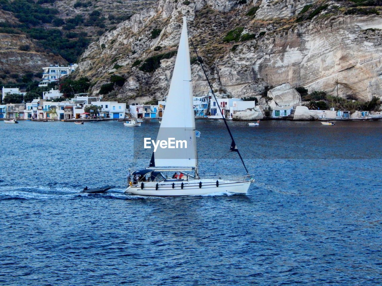 SAILBOATS SAILING ON SEA AGAINST MOUNTAIN