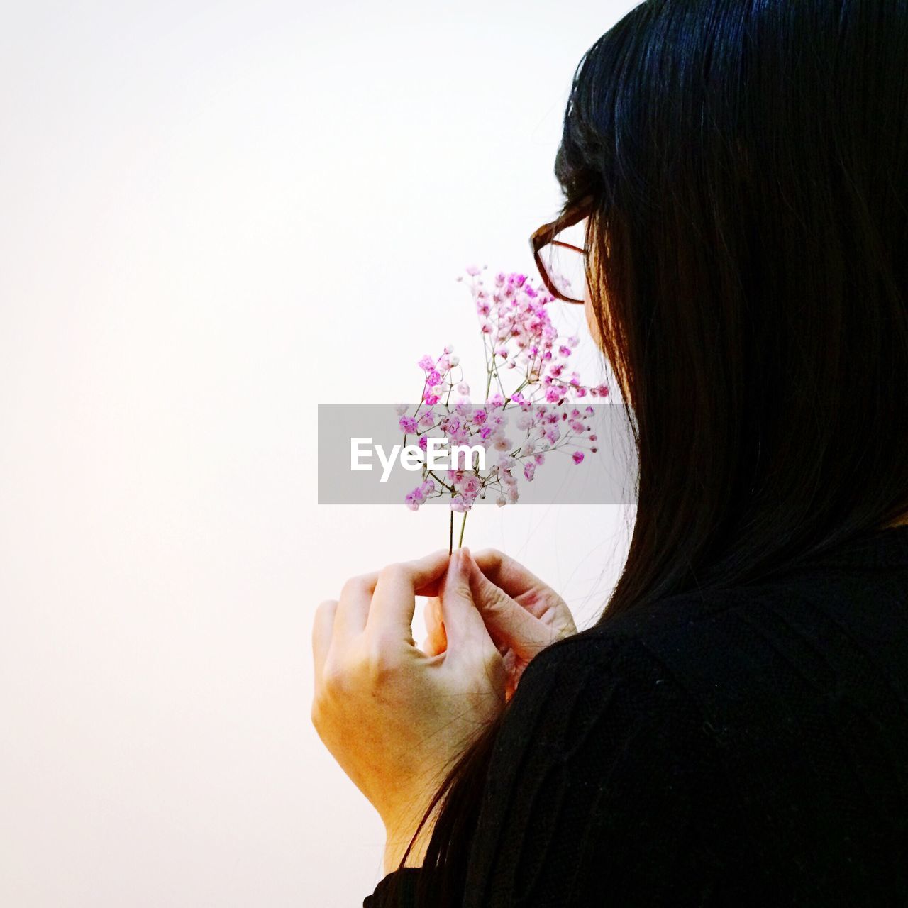 Close-up of woman holding flowers against white background