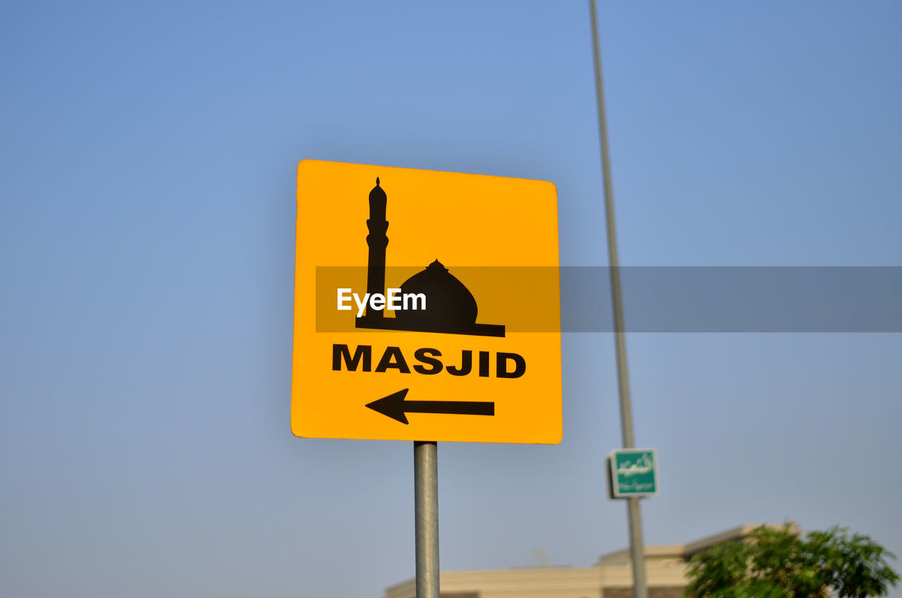 Close-up of road sign against sky 