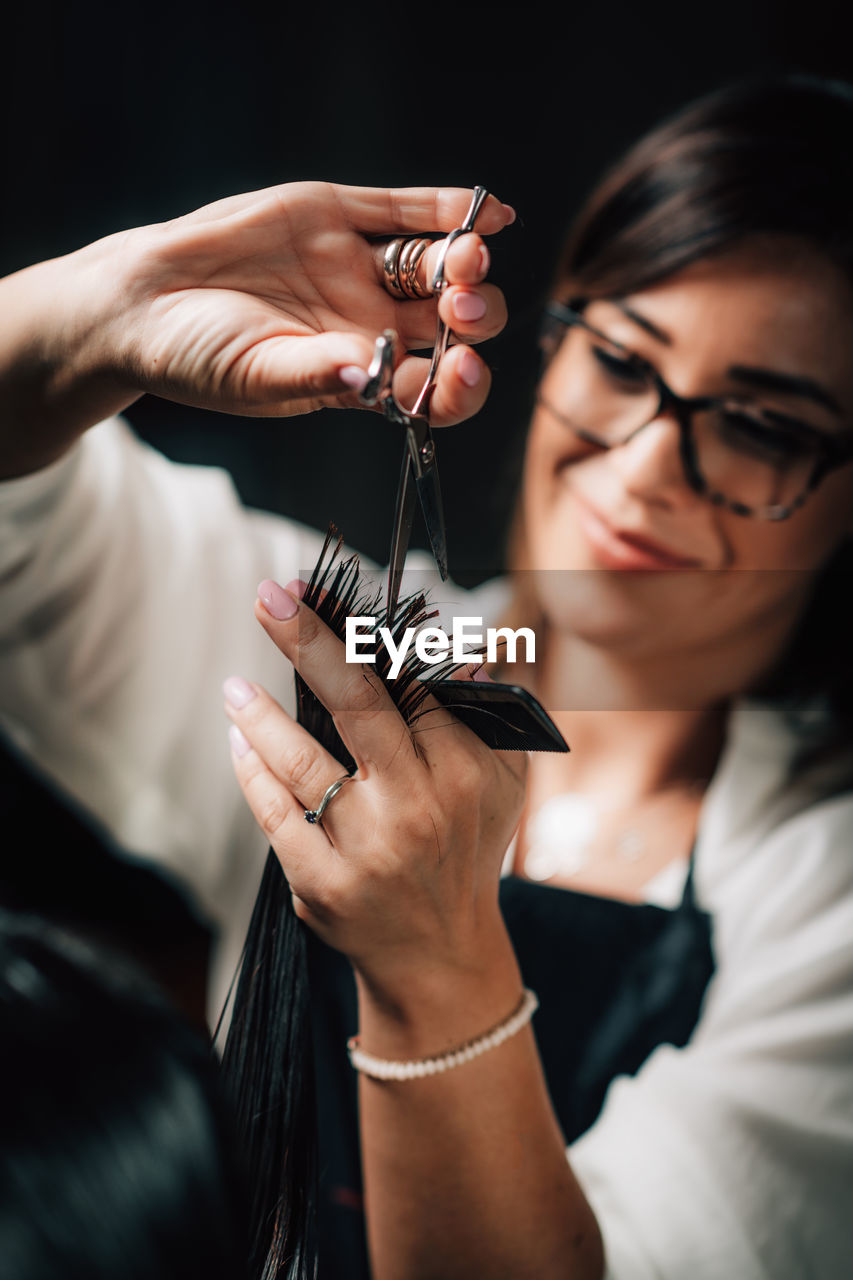 Midsection of hairdresser cutting woman hair in salon