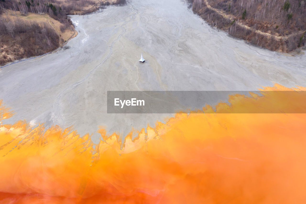 Aerial view of a toxic waste lake, with yellow chemical residuals flooded a church. geamana, romania