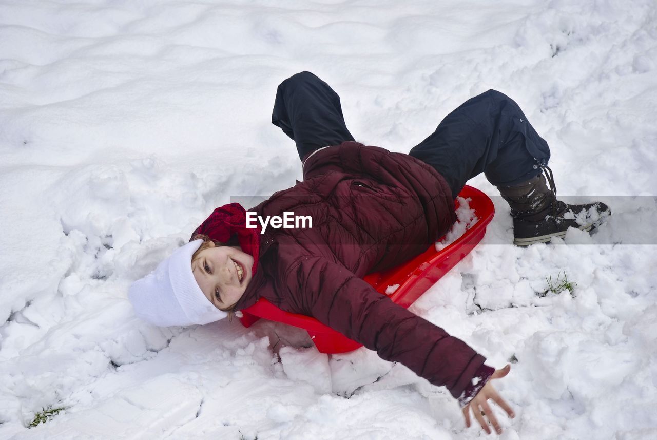 High angle view portrait of girl lying on snow