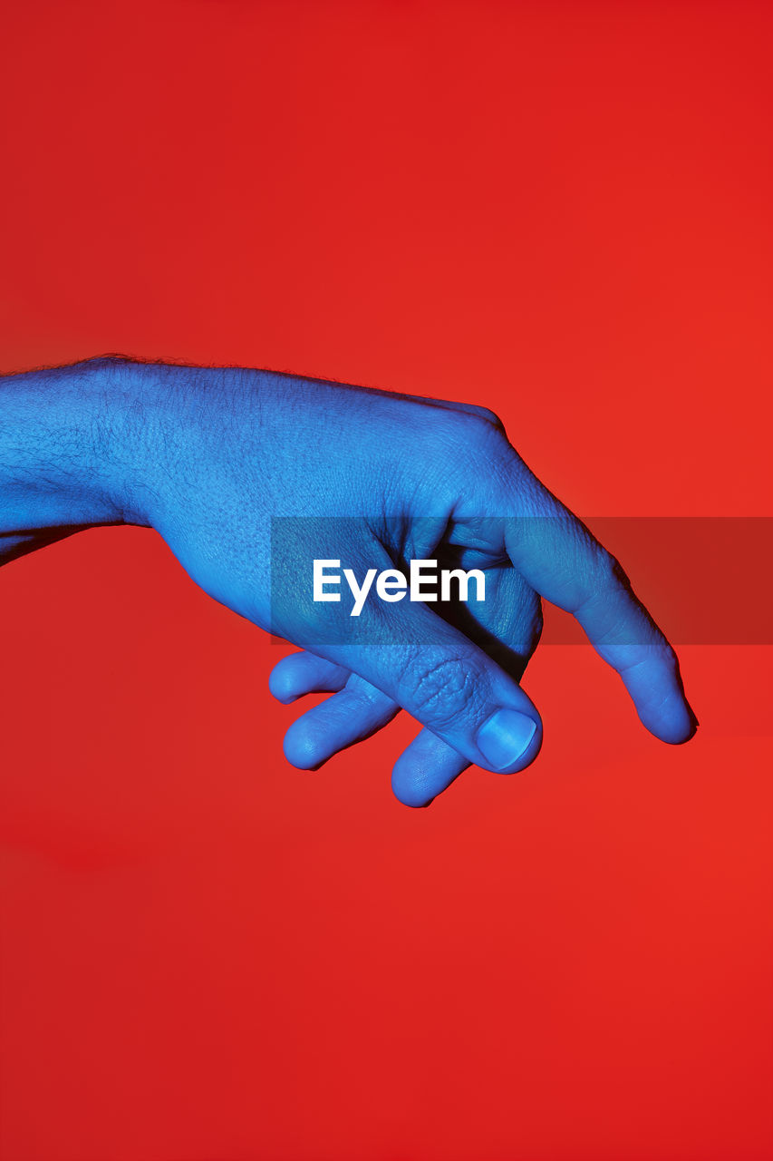 Man's blue finger pointing downwards over red background. isolated vertical photo person