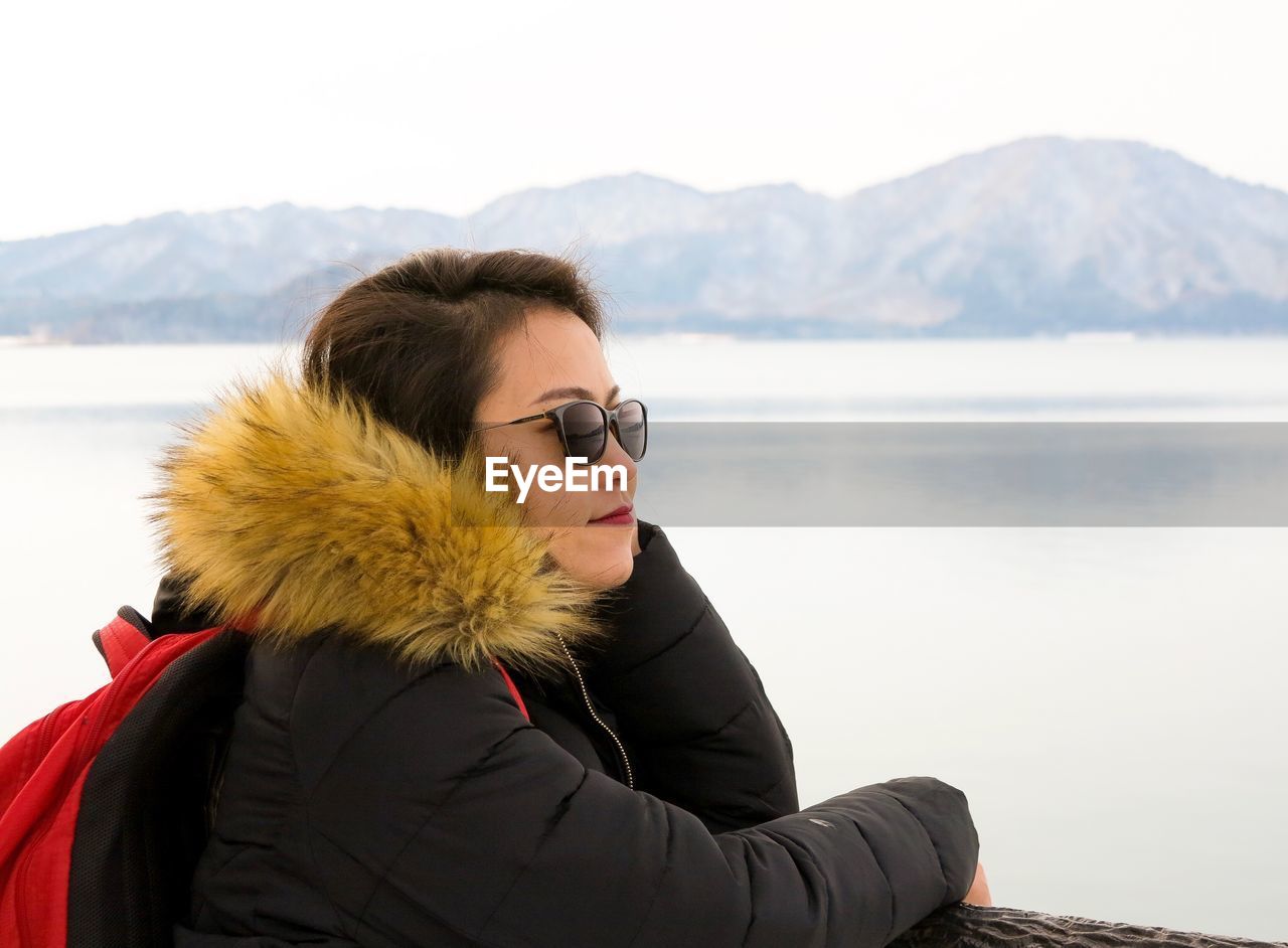 Close-up of woman wearing warm clothing against lake