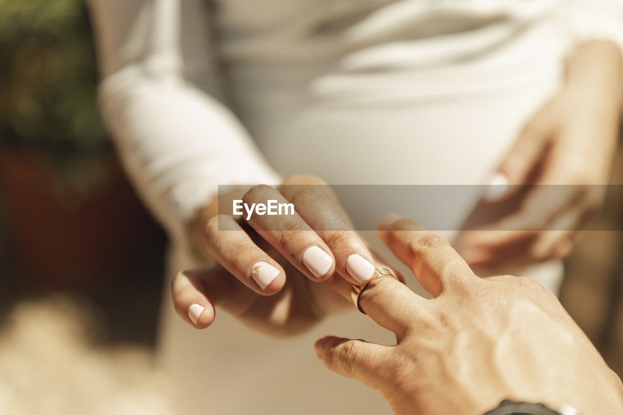 Hand of bride putting wedding ring on groom's finger