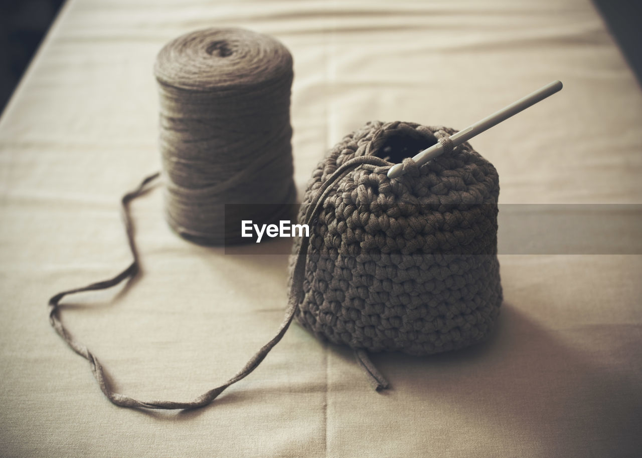 Half-finished woolen purse with spool on table