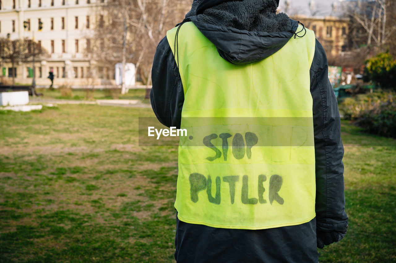 Rear view of person wearing neon vest with stop putler text message