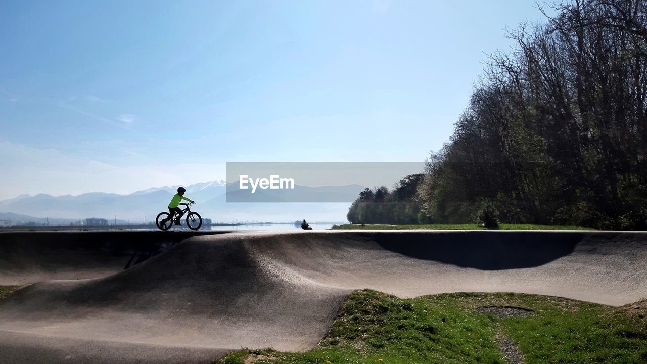 Child riding bicycle on pumptrack against sky