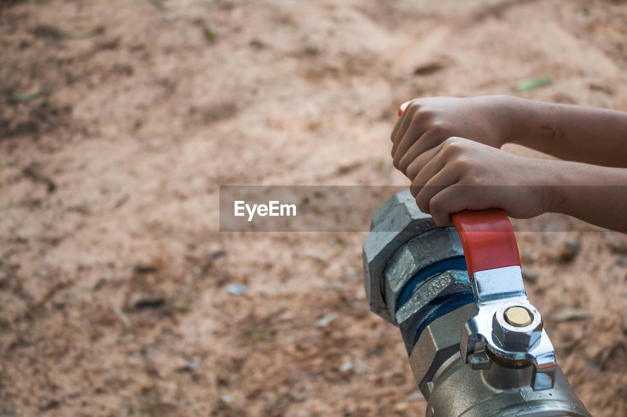 Cropped hands holding lever of water pipe