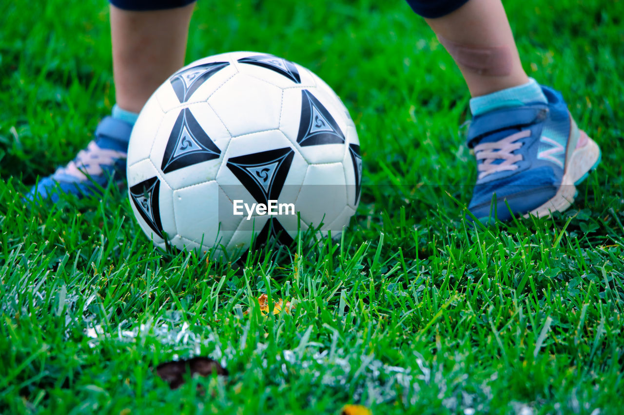 LOW SECTION OF BOY PLAYING SOCCER BALL