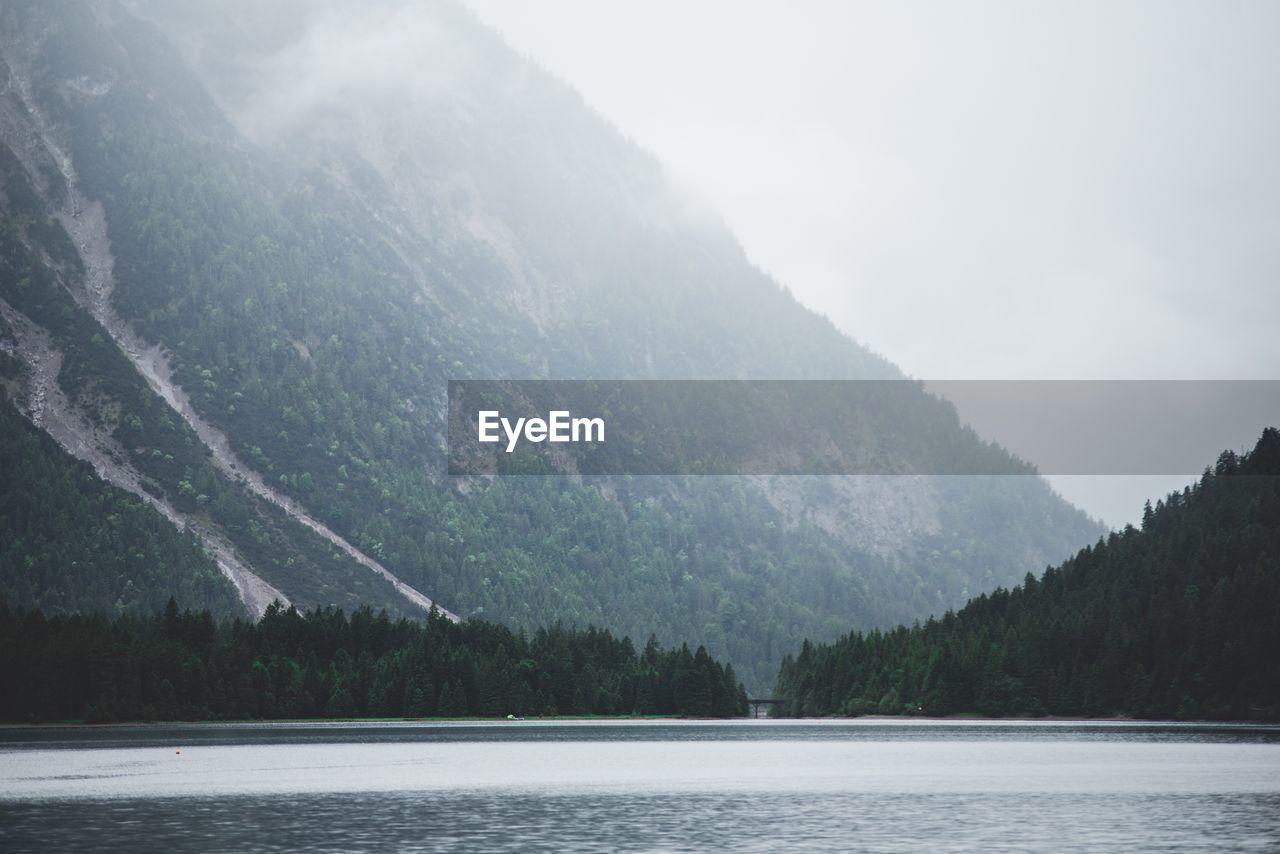 Scenic view of lake by mountains against sky