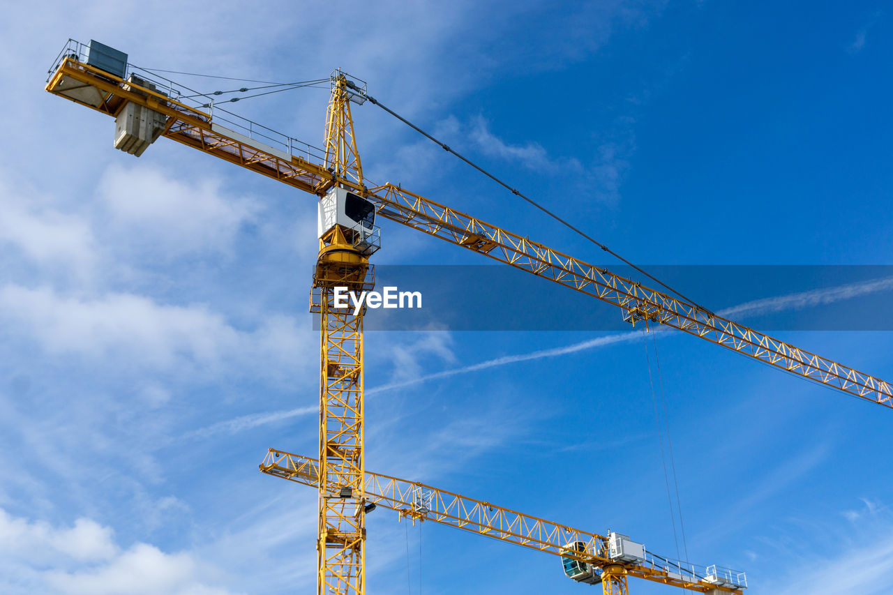 LOW ANGLE VIEW OF CRANE AGAINST BLUE SKY