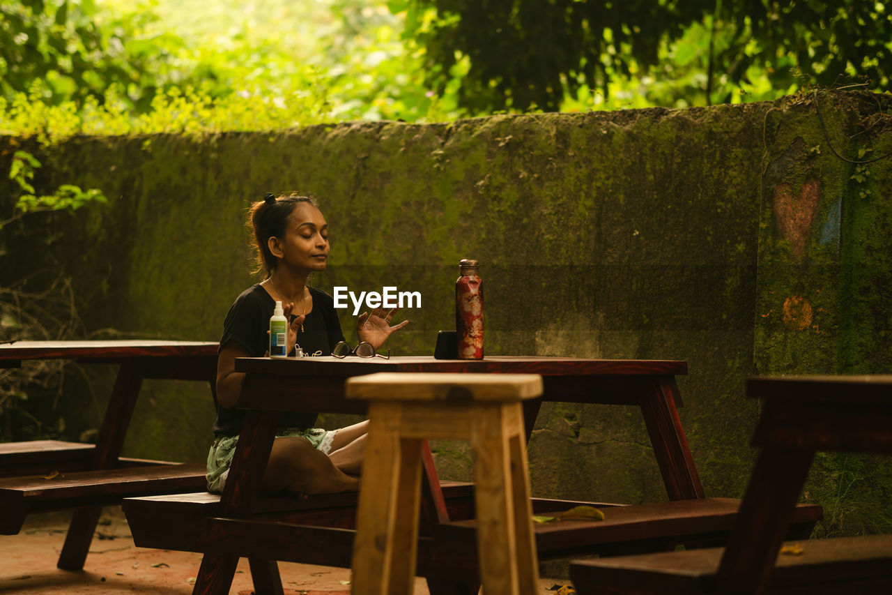 Side view of woman sitting on table