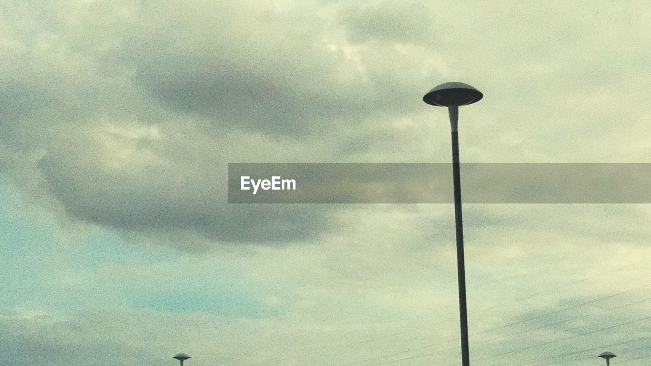 LOW ANGLE VIEW OF STREET LIGHTS AGAINST CLOUDY SKY